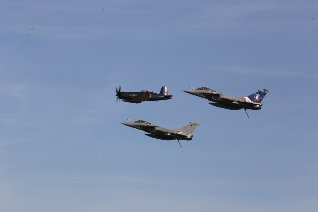 Drie gevechtsvliegtuigen in formatie boven een blauwe lucht.