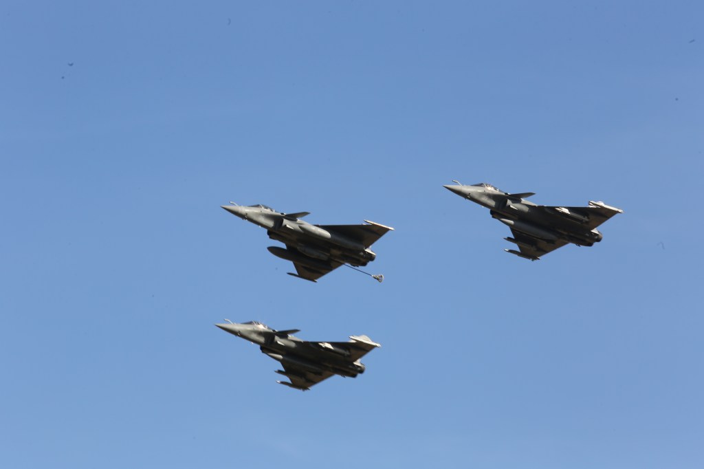 Drie combatvliegtuigen vliegen in formatie tegen een blauwe lucht.