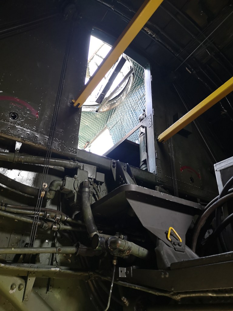 Zicht op het interieur van een machine met zichtbare leidingen en een open raam boven.